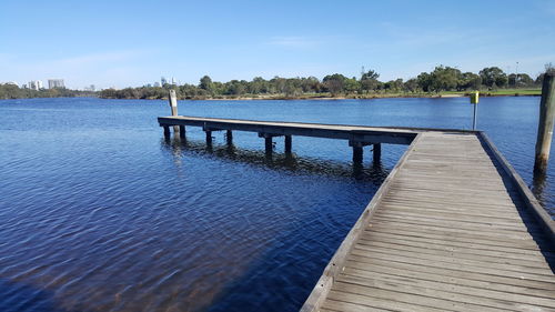 Jetty over lake against blue sky