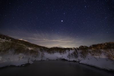 Scenic view of snowcapped mountains and frozen lake against sky at night