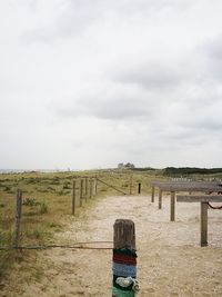 Wooden post on field against sky