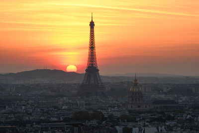 Communications tower in city during sunset