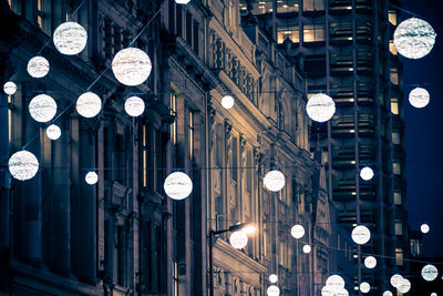 Low angle view of lanterns hanging by building at night during christmas