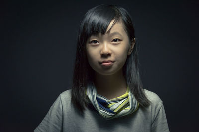 Close-up portrait of girl against black background