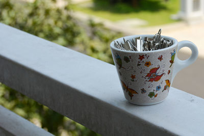 Portrait of a tiny cup filled with metal binder clips on a white surface 