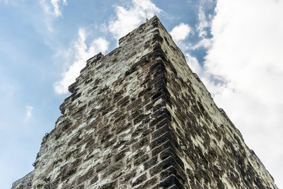 The ruins of a historical tower against a blue sky with white clouds.