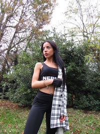 Portrait of beautiful young woman standing against trees