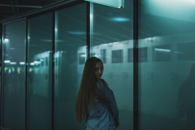 Portrait of young woman standing by window