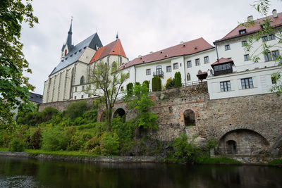 Arch bridge over river by building against sky