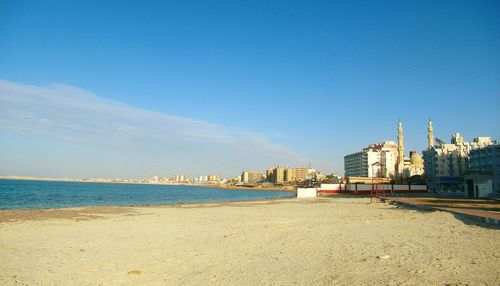 View of beach and buildings against blue sky