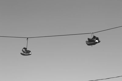 Low angle view of shoes hanging on cable against sky