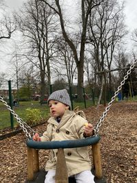 Boy sitting on bare tree