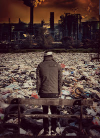 Rear view of man sitting by buildings in city