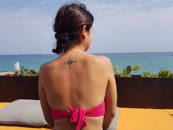 Rear view of woman at beach resort against sky