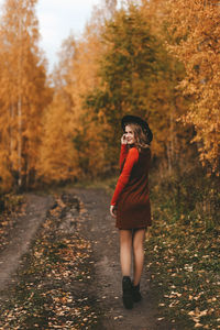 A pretty girl enjoys solitude drinks coffee walks in the autumn forest in nature in fall