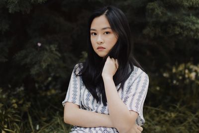 Portrait of woman standing against trees