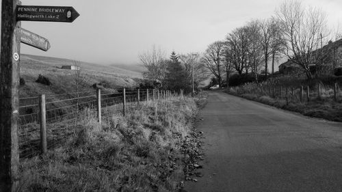 Road amidst bare trees against clear sky