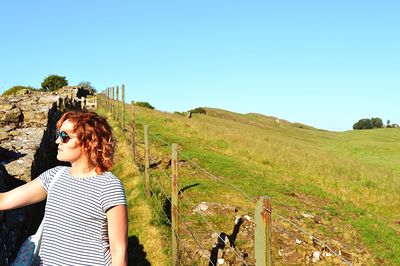 Woman standing on field against clear sky