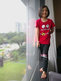 Full length of girl standing against wall