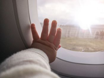 Cropped image of baby touching window in airplane