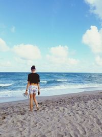 Rear view of woman walking on sandy beach