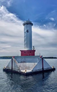 Lighthouse by sea against sky