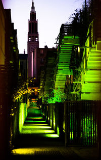 Illuminated footpath amidst buildings in city at night