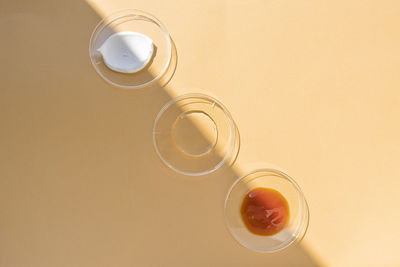 Samples of cosmetic products in glass containers on a beige background, top view. 