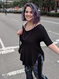 Portrait of smiling young woman standing on road