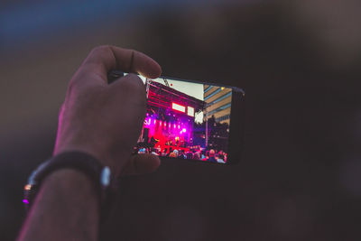 Close-up of hand holding illuminated mobile phone at night