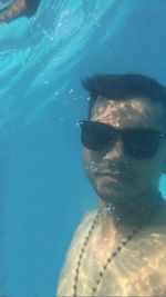 Close-up portrait of young woman swimming underwater