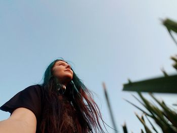 Low angle view of young woman against clear sky