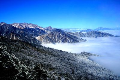 Scenic view of snowcapped mountains against blue sky