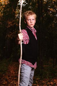 Portrait of boy holding stick while standing in forest