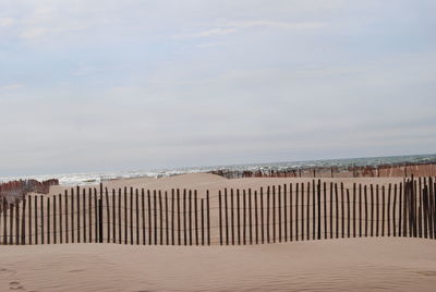 Wooden posts on beach against sky