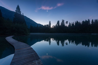 Reflection of trees in lake against blue sky