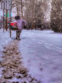 Man walking on snow covered plants in city