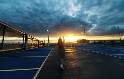 People walking on road against cloudy sky