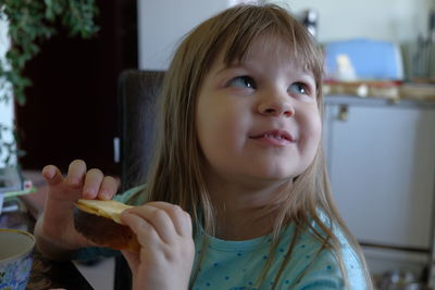 Close-up of cute girl holding food at home