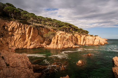 Rock formations by sea against sky