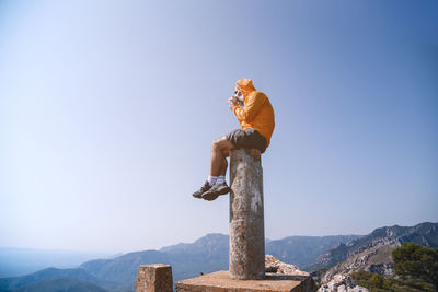 Lonely moment. the man sits on top of the rock and watches the valley having a coffee