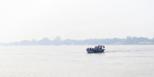 People in boat on sea against clear sky