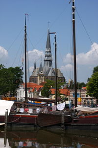 Sailboats moored on canal in city against sky