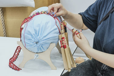 Girl's hands spin braid on bobbins.