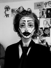 Portrait of woman with face paint standing against wall