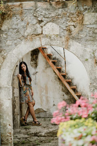 Full length of woman standing by wall in alley