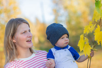 Woman with baby boy looking away during autumn
