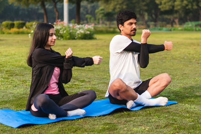 Side view of woman using mobile phone while sitting on field