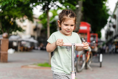 Cute girl standing on push scooter outdoors