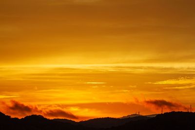 Scenic view of silhouette mountains against orange sky