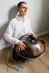 Man playing on hang drum, or steel drum, hangpan, modern steel music instrument at home. meditation