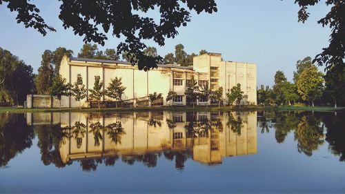 Reflection of building in lake against sky in city
